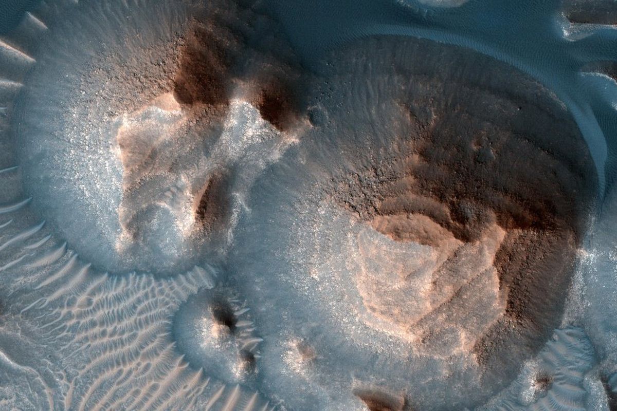 Beberapa kawah di Arabia Terra, planet Mars yang dipenuhi dengan batuan berlapis, sering tersingkap dalam gundukan bulat. Gambar itu diambil kamera, Eksperimen Pencitraan Resolusi Tinggi, di Mars Reconnaissance Orbiter NASA. Ilmuwan NASA mengkonfirmasi adanya ribuan letusan gunung berapi purba di Mars.