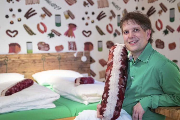 Claus Bober, pemilik hotel sosis Boebel Bratwurst Bed and Breakfast, dengan latar belakang kamar hotelnya yang serbasosis.