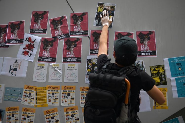 Seorang demonstran menempelkan poster di tembok dukungan gerakan demokrasi atau Lennon Wall yang ada di Hong Kong.