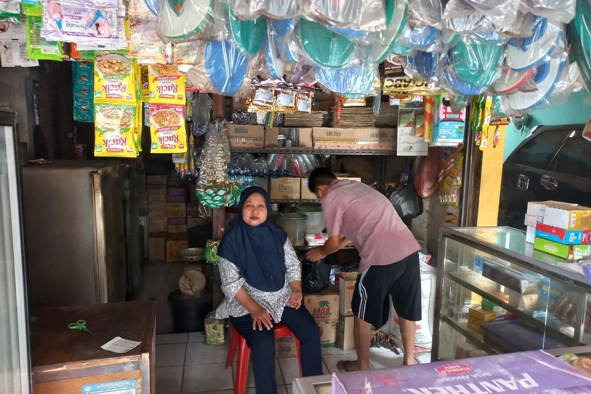 Sutiyah (46) tengah menjaga warung kelontongannya meski kepulan asap yang berasal dari TPA Rawa Kucing, Neglasar, Tangerang, masih menyeruak pada Kamis (26/10/2023).