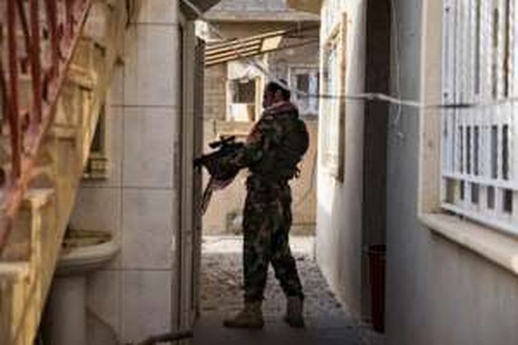 Seorang anggota pasukan Peshmerga sedang memeriksa bangunan di Bashiqa, Irak.  