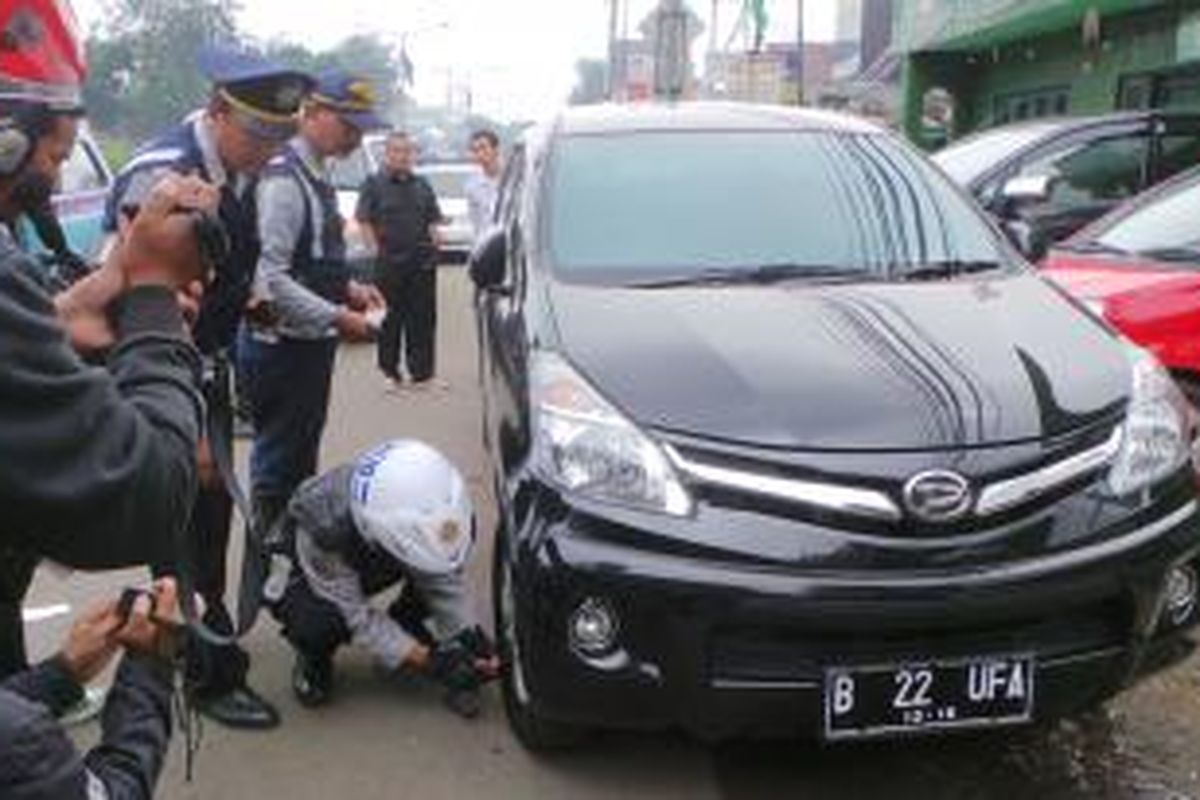 Petugas Dishub mengempiskan salah satu ban kendaraan yang diparkir dipinggiran jalan Otista Raya, Jatinegara, Jaktim. Selasa (18/3/2014).