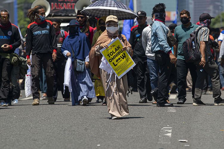 Seorang buruh membawa poster protes dalam aksi unjuk rasa di depan kompleks Parlemen, Senayan, Jakarta, Selasa (25/8/2020). Dalam aksinya itu ribuan buruh menolak omnibus law draf pemerintah dan menuntut agar PHK massal dampak COVID-19 dihentikan.