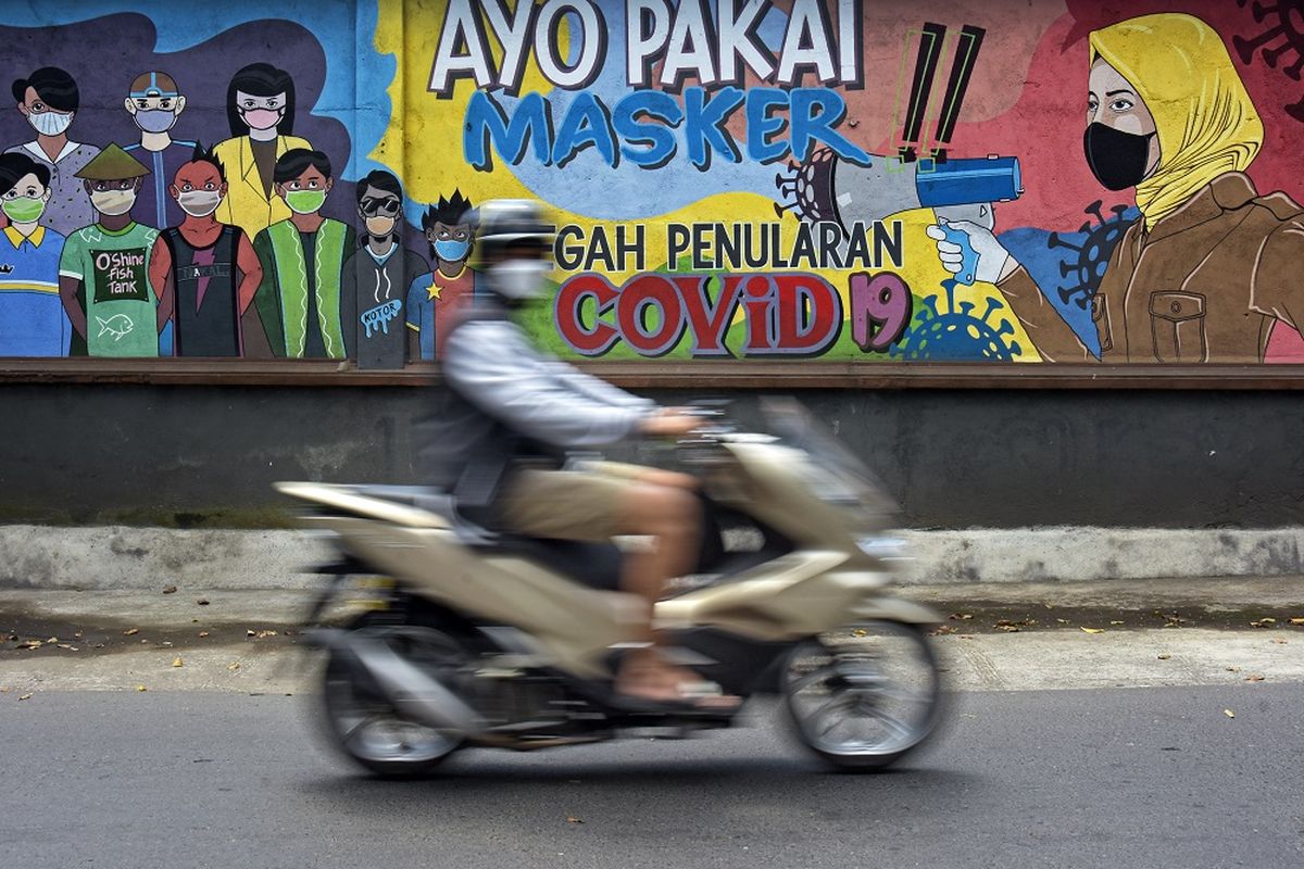 Pengendara sepeda motor melintas dekat mural bertemakan disiplin bermasker untuk pencegahan penularan COVID-19 di Mataram, NTB, Minggu (29/8/2021). ANTARA FOTO/Ahmad Subaidi/rwa.