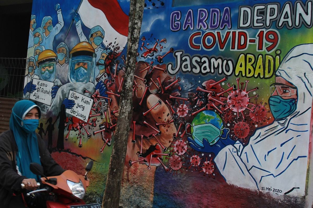 Pengendara motor melintas di depan mural yang bergambar dukungan untuk tenaga medis yang ada di Kavling Kinayung Pondok Aren, Tangerang Selatan, Banten, Jumat (15/5/2020). Mural yang dibuat oleh warga itu bertujuan untuk memberikan dukungan dan apresiasi atas perjuangan tenaga medis yang menjadi garis terdepan dalam penanganan COVID-19. ANTARA FOTO/Muhammad Iqbal/wsj.