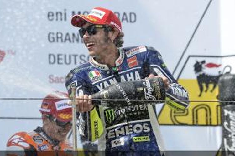 Pebalap Yamaha Factory Racing, Valentino Rossi, membuka dan menyemburkan sampanye untuk merayakan suksesnya finis ketiga GP Jerman di Sirkuit Sachsenring, Minggu (14/7/2013).