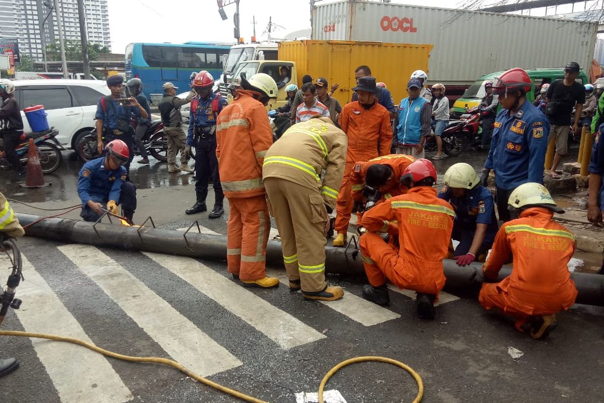 Petugas Damkar Jakarta Barat berusaha memotong papan reklame yang roboh di Cengkareng, Jakarta Barat, Sabtu (28/12/2019)