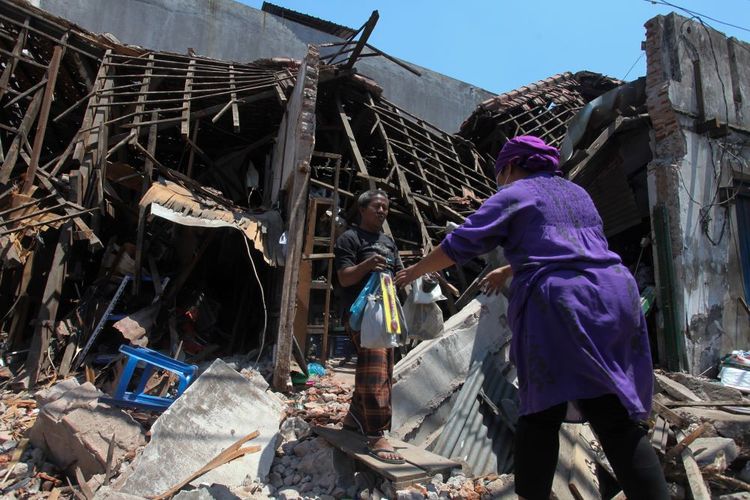 Pedagang mengevakuasi barang dagangan dari tokonya yang ambruk di Jalan Kapasari, Surabaya, Jawa Timur, Selasa (5/9/2023). Bangunan berbentuk kopel yang terdapat tiga toko suku cadang sepeda motor baru dan bekas itu ambruk pada Senin (4/9/2023) tengah malam saat adanya pengerjaan box culvert atau gorong-gorong di dekat bangunan itu. ANTARA FOTO/Didik Suhartono/nz