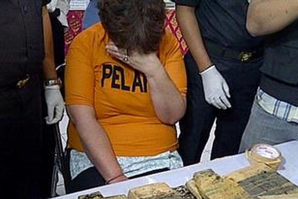 Lindsay June Sandiford (53) menutupi wajahnya saat konferensi pers di Kantor Bea Cukai Ngurah Rai, Senin (28/5/2012).  