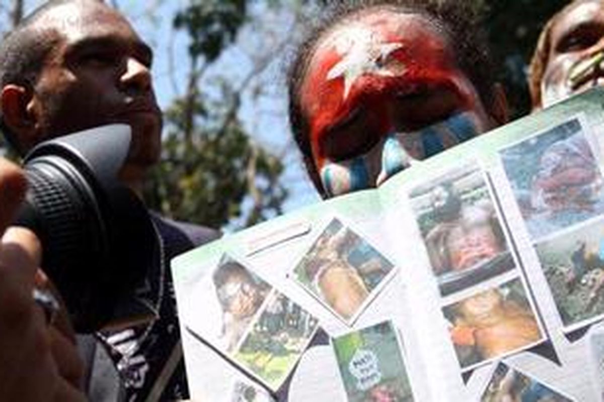Salah seorang pendemo yang mengecat wajahnya dengan simbol Bendera Papua, Bintang Kejora membawa poster yang berisi foto-foto kekerasan yang dialami warga Papua. Ratusan pendemo yang tergabung dalam Solidaritas Pelajar, Mahasiswa, Pemuda dan Masyarakat Papua (SPMPMP) Di Sulawesi Utara berdemo menuntut keadilan di taha Papua, Selasa (23/10/2012)