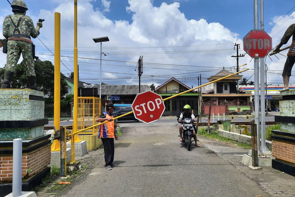 Agus Suyitno (61), saat menjaga perlintasan sebidang rel kereta api di Desa Sambigede, Kecamatan Sumberpucung, Kabupaten Malang, Kamis (9/12/2021).