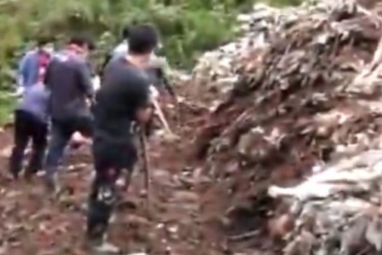Petugas penyelamat di Zhenxiong, China, terlihat berusaha  menggali tumpukan sampah di mana dua kakak beradik tewas tertimbun pada Selasa (10/7/2018).