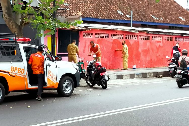 Aparat kelurahan Sentul, Kecamatan Kepanjenkidul, Kota Blitar menghapus mural dan coretan bernada kritikan kepada pemerintah di sebuah bidang tembok di Jalan Moh Hatta menjelang kedatangan Presiden Jokowi, Selasa (7/9/2021)