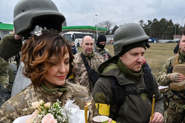 Prajurit pertahanan teritorial Ukraina, Valery dan Lesya, menikah tidak jauh dari pos pemeriksaan di pinggiran Kyiv pada 6 Maret 2022. 