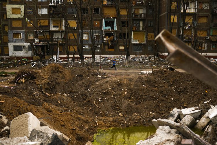 Seorang pemuda lokal melewati kawah akibat serangan Rusia pada awal Mei di seberang sebuah gedung apartemen di Kramatorsk, Ukraina timur, Sabtu, 21 Mei 2022. 