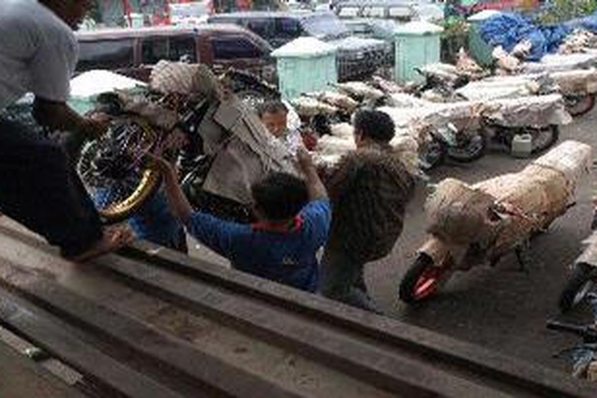 Sejumlah pekerja di tempat pengiriman paket di Stasiun Kereta Api Pasar Senen, Jakarta Pusat, sedang mengangkat sepeda motor ke atas truk untuk dikirim ke Surabaya, Jawa Timur, Kamis (13/11/2003).