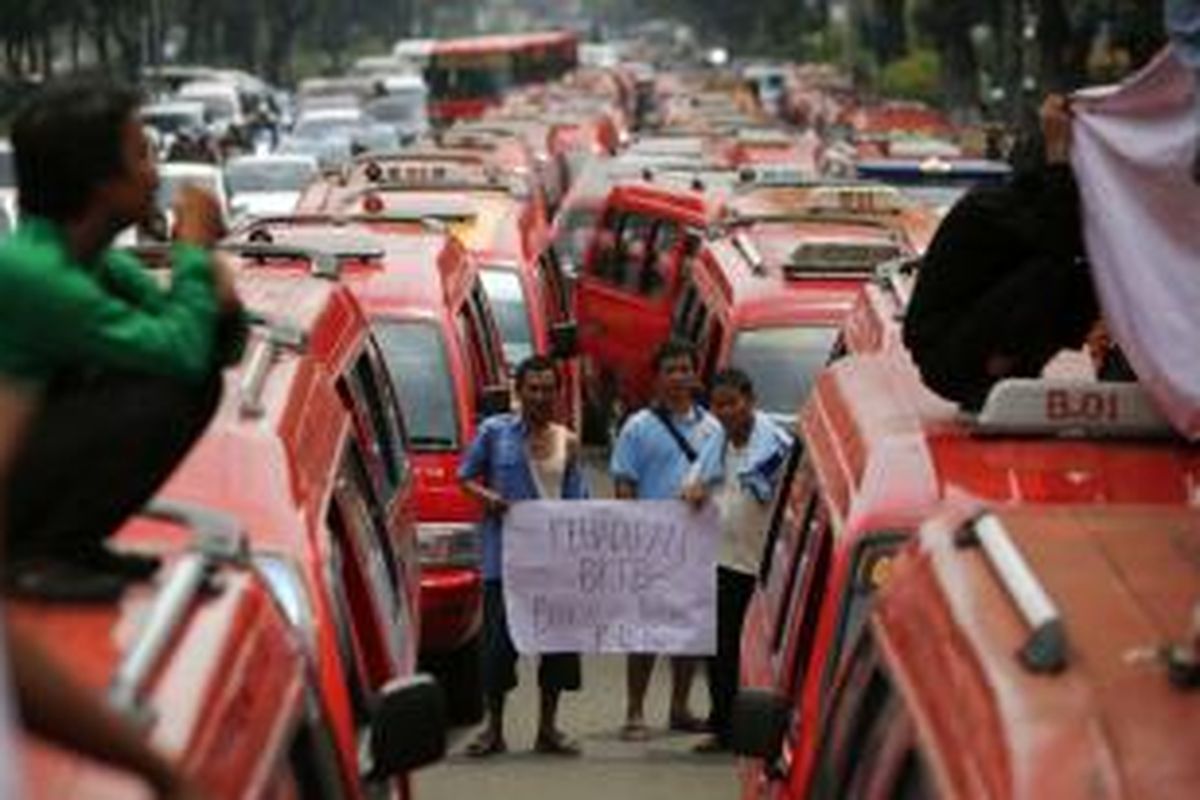 Para sopir angkutan kota Koperasi Wahana Kalpika (KWK) jurusan Grogol - Muara Karang berunjuk rasa di depan Balaikota DKI Jakarta, Selasa (11/2/2014). Mereka menolak beroperasinya bus kota terintegrasi busway (BKTB) karena dianggap menurunkan pendapatan mereka.