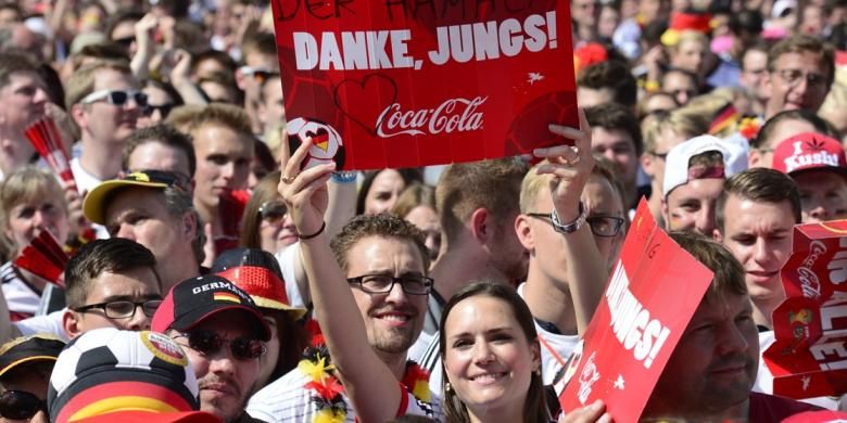 Suporter Jerman membentangkan spanduk bertuliskan rasa terima kasih kepada para pemain skuad Der Panzer yang sukses meraih gelar juara Piala Dunia 2014. Mereka berkumpul di Gerbang Brandenburg, Berlin, untuk menyambut Mario Goetze dan kawan-kawan. 