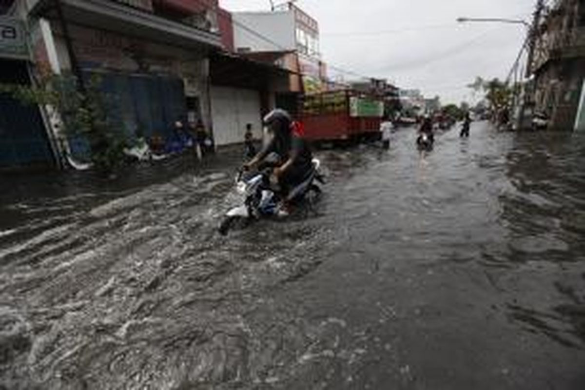 Pengendara melintasi banjir di Jalan Kramat Jaya, Jakarta Utara, Rabu (12/3/2014). Hujan deras mengakibatkan banjir setinggi hingga 50 sentimeter di kawasan tersebut sejak pagi. KOMPAS/LUCKY PRANSISKA