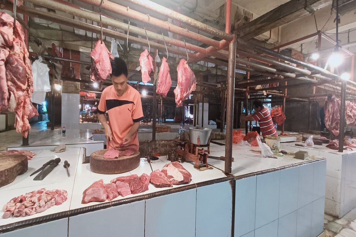 Khoir (28), salah satu pedagang daging sapi di Pasar Tradisional Pondok Gede sedang memotong daging sesuai permintaan pembeli, Minggu (18/12/2022). Harga daging sapi menjelang natal 2022 dan tahun baru 2023 masih tergolong aman dan cukup stabil.