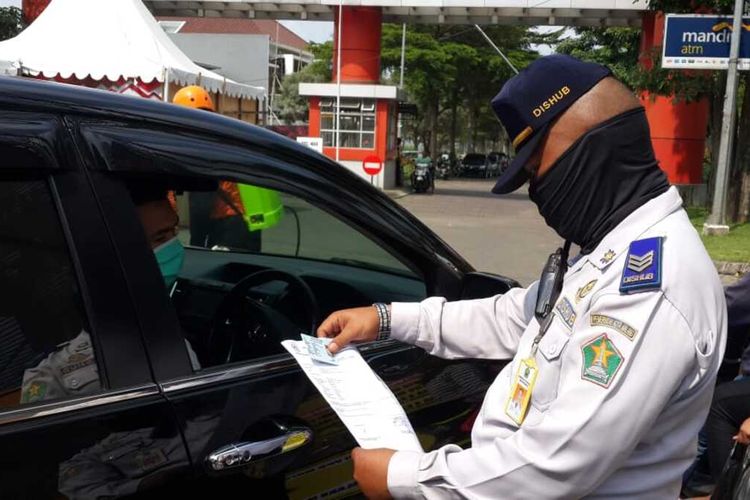 Petugas memeriksa seorang pengendara asal luar daerah yang mau masuk ke Kota Malang pada Minggu (17/5/2020).
