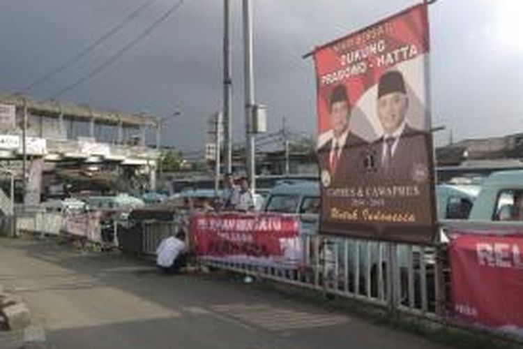 Tim relawan Jokowi-JK pasang spanduk di dekat spanduk Prabowo-Hatta, di Terminal Kampung Melayu, Jakarta Timur, Rabu (18/6/2014)