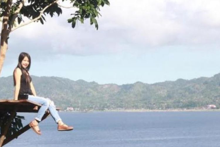 Berfoto di Rumah Pohon Urongo dengan latar belakang pesona Danau Tondano di Sulawesi Utara. 