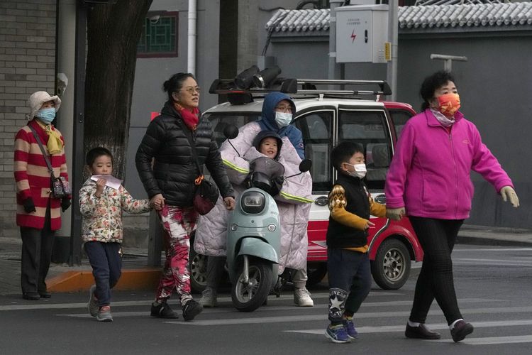 Sejumlah warga yang beberapa di antaranya memakai masker, menyeberang jalan di Beijing, China, Rabu (20/10/2021). Ibu kota China mulai menawarkan vaksin booster Covid-19, empat bulan sebelum Beijing dan wilayah sekitarnya menggelar Olimpiade Musim Dingin.
