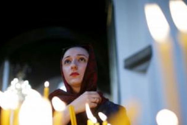 Seorang perempuan berdoa di Katedral Echmiadzin yang menjadi pusat upacara kanonisasi ini. 