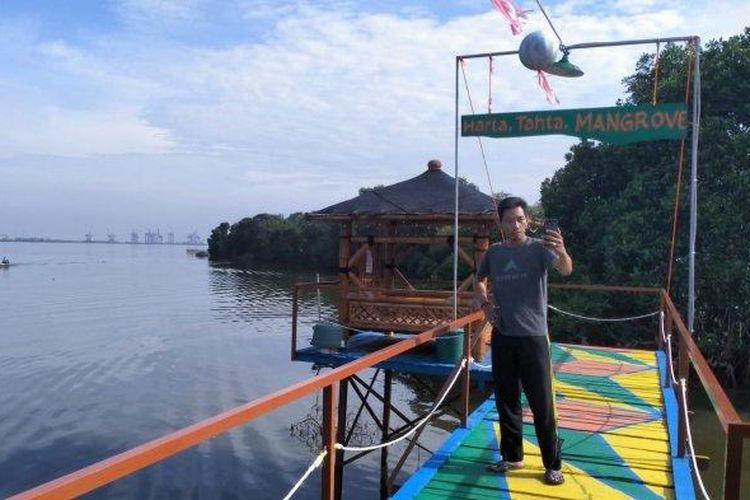 Seorang pengunjung sedang asyik berfoto di Kampung Pelangi Greges Timur, salah satu tempat wisata Surabaya yang bisa dikunjungi.