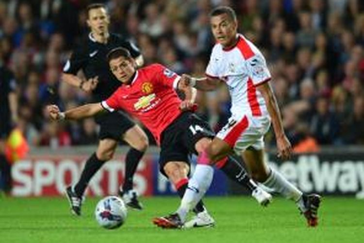 Striker Manchester United, Javier Hernandez (kiri) mengoper bola di belakang gelandang Milton Keynes Dons, Dele Alli, pada babak kedua Piala Liga, Selasa (26/8/2014).