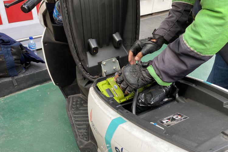 Seorang driver ojek online mengganti baterai motor listrik di salah satu SPKLU di SPBU MT Haryono