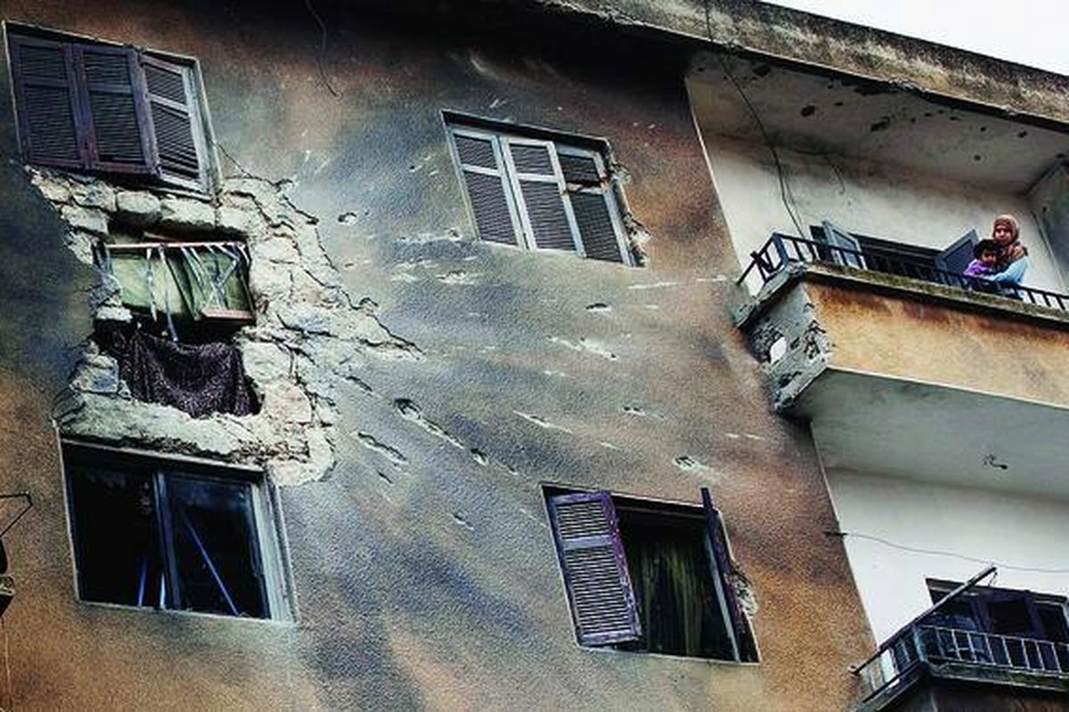 Seorang perempuan menggendong putrinya di balkon tempat tinggalnya yang rusak parah karena serangan bom pasukan Pemerintah Suriah di pusat kota Idlib, Suriah, Senin (27/2). Para menteri luar negeri Uni Eropa mengatakan terkejut dengan meningkatnya kekerasan yang dilakukan Pemerintah Suriah terhadap warganya, dan menerapkan sanksi baru untuk menekan rezim Bashar al-Assad agar mau menghentikan kekerasan.