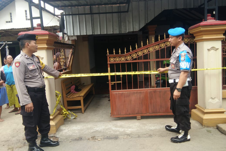 Petugas berjaga di depan rumah lokasi penemuan ibu rumah tangga yang tewas dengan luka di leher di Desa Nyawangan, Kecamatan Kras, Kabupaten Kediri, Jawa Timur, Senin (27/5/2019).