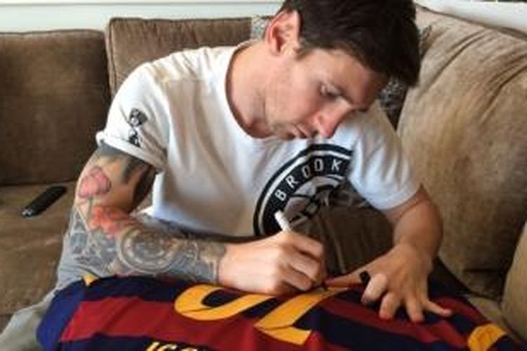 Lionel Messi menandatangani seragam Barcelona bernomor 10 untuk diberikan kepada Ronaldinho.