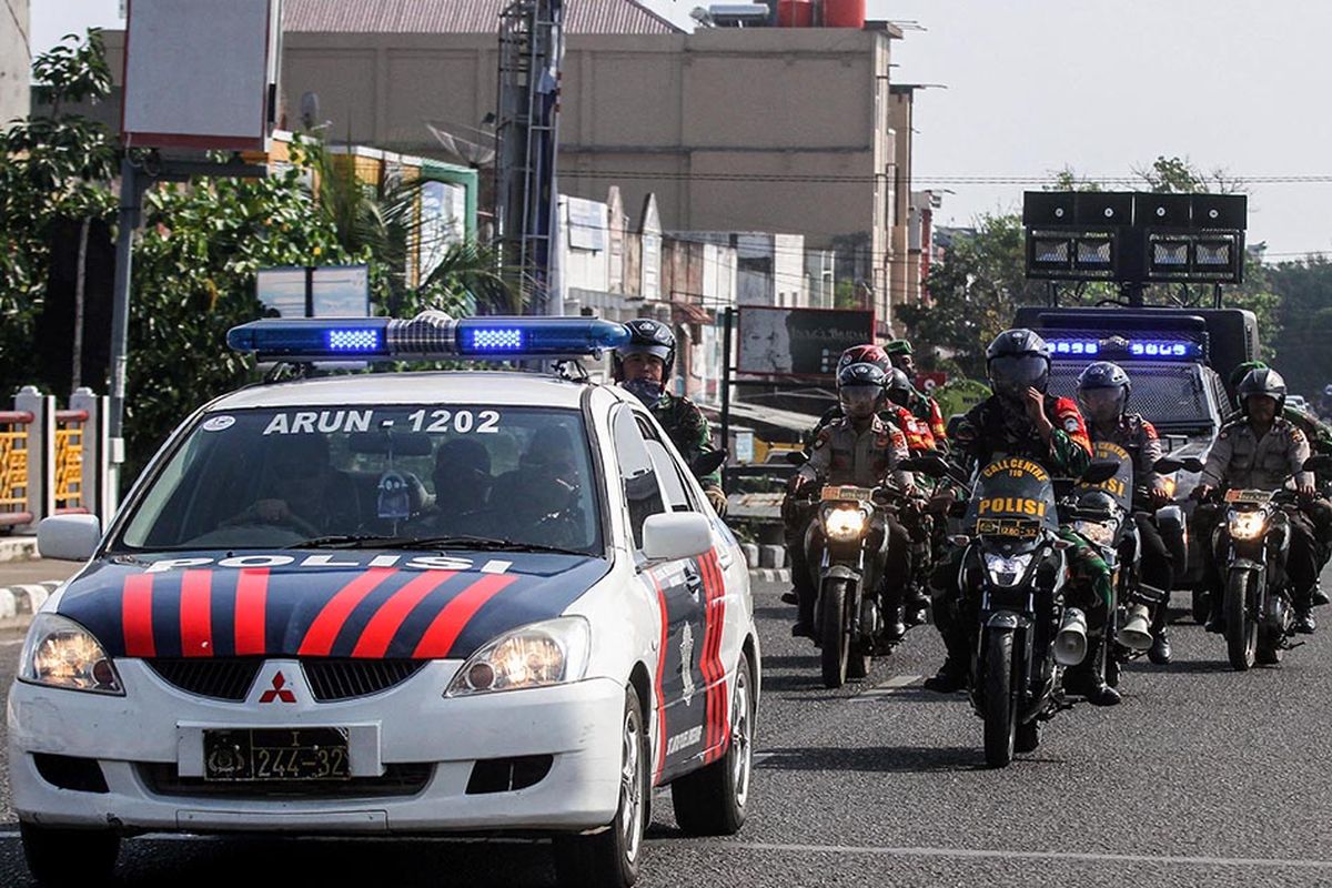 Personel gabungan dari Babinsa TNI dan Babinkamtibmas Polri melintas saat berpatroli mensosialisasikan antisipasi pandemi virus Corona (COVID-19) di Lhokseumawe, Aceh, Selasa (31/3/2020). TNI-Polri di Lhokseumawe menggencarkan patroli gerakan pencegahan secara masif dan serentak dengan mensosialisikan pemberlakuan jam malam hingga pelosok desa untuk meminimalisir penyebaran COVID-19.