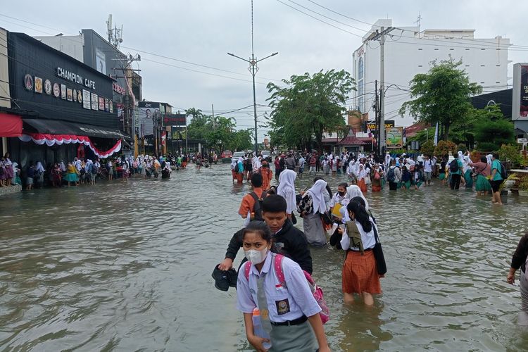 Sejumlah pelajar sekolah dan warga di lokasi terjadinya banjir di Jalan Dr Mansyur, Medan, Kelurahan Selayang I, Kecamatan Medan Selayang pada Kamis (18/8/2022).