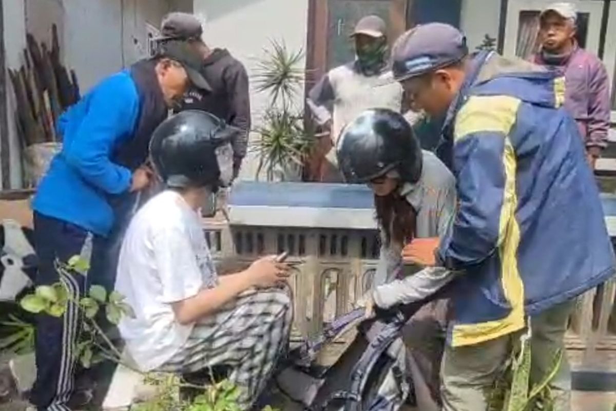 Sejumlah warga mengevakuasi dua wisatawan asal China usai motor matic yang mereka naiki terjun ke sawah. 
