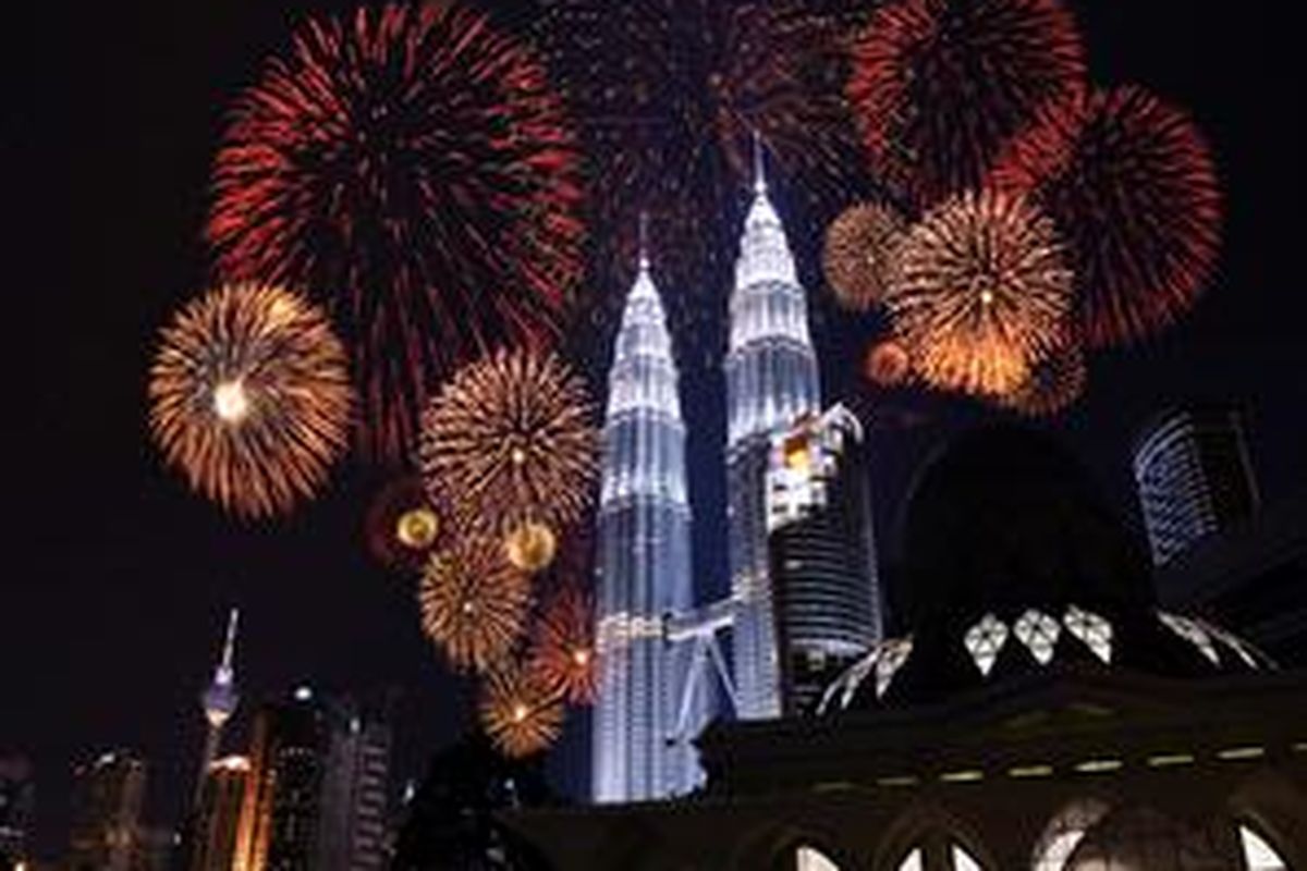 Menara Petronas, gedung kembar yang menjadi salah satu ikon pariwisata Malaysia gemerlap oleh pijar kembang api di waktu malam. 