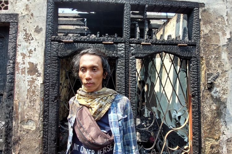 Iang (26) salah satu korban kebakaran di Tambora, melihat api muncul dari sebuah rumah kontrakan kosong yang berada tepat di depan rumahnya, pada Selasa (26/7/2022).