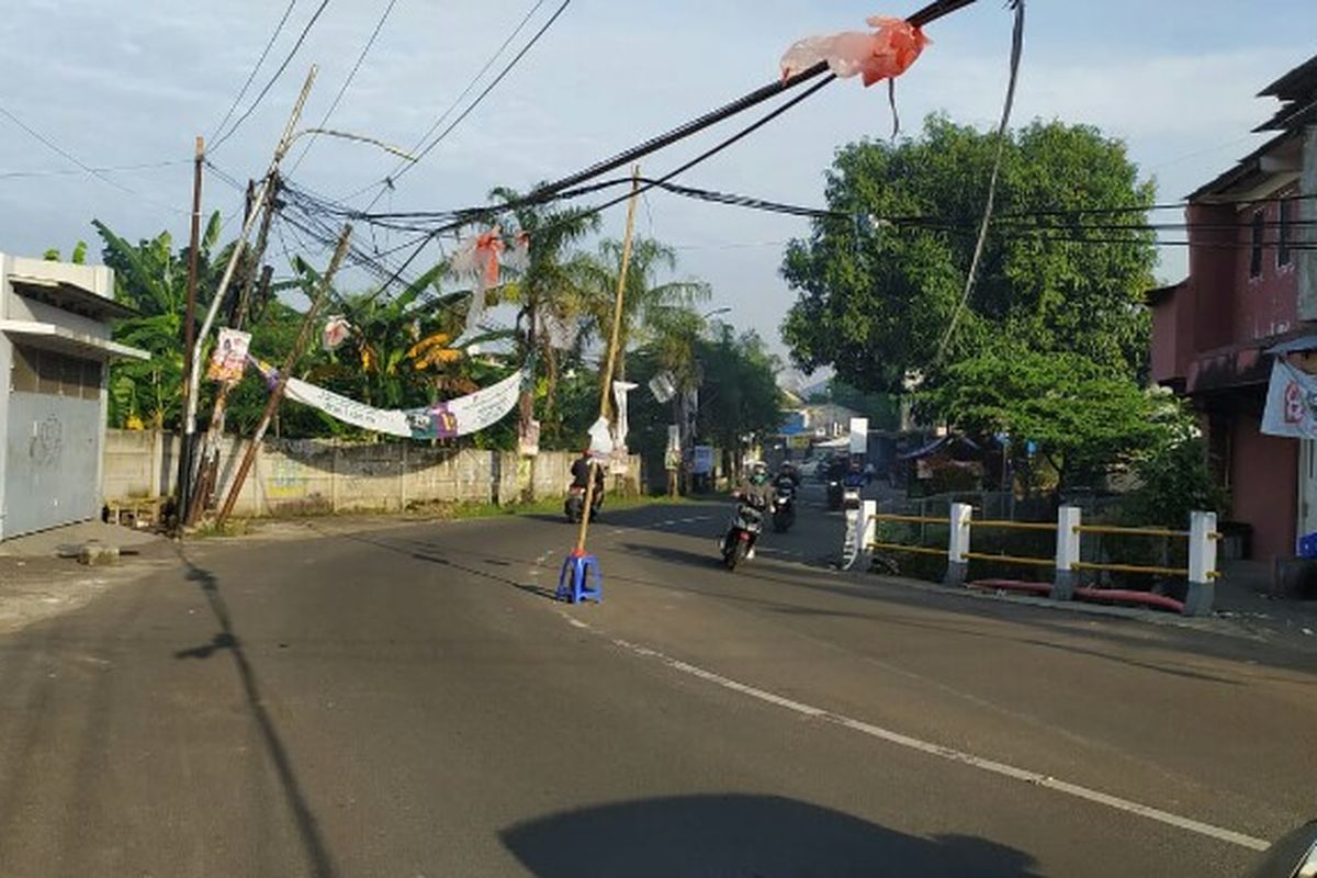 Sebuah kabel menjuntai yang disangga bambu di Jalan Purnawarman, Kelurahan Pisangan, Ciputat, Tangerang selatan, membuat pengendara was-was. 