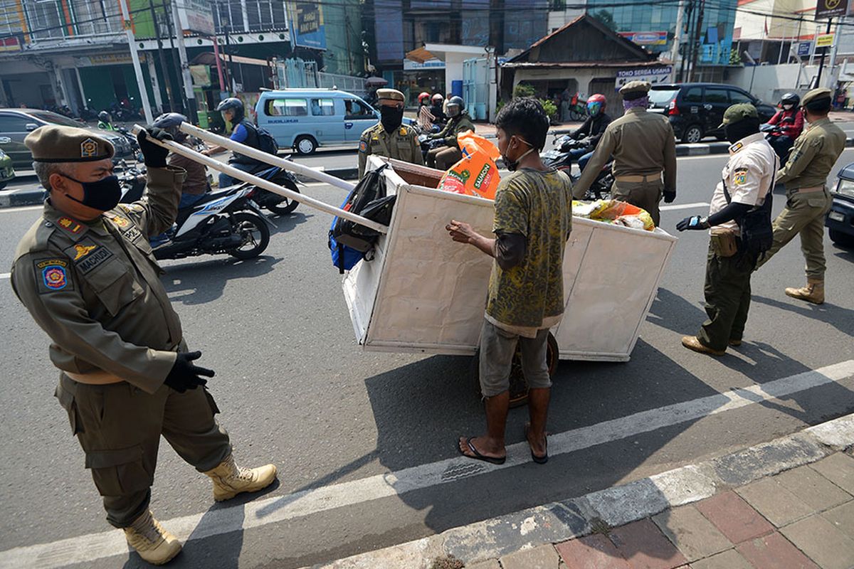 Sejumlah petugas Satpol PP mengamankan seorang penyandang masalah kesejahteraan sosial (PMKS) di Jalan Dewi Sartika, Cawang, Jakarta, Rabu (29/4/2020). Pemerintah Provinsi DKI Jakarta menggalakkan penertiban PMKS yang berkeliaran saat penerapan pembatasan sosial berskala besar (PSBB) untuk mencegah penyebaran COVID-19.