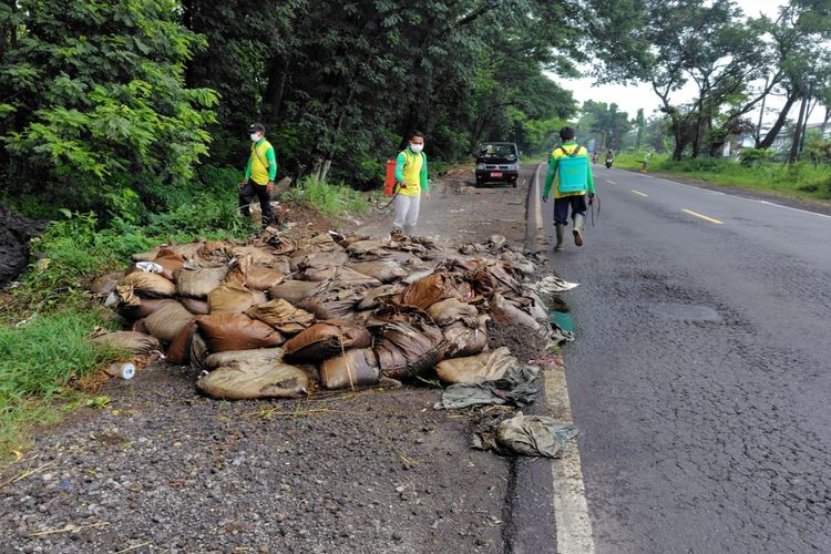 BERSIHKAN--Petugas DLH Ngawi membersihkan limbah kotoran yang dibuang ditepi Jalan Ngawi - Solo tepatnya di Desa Kauman, Kecamatan Widodaren, Kabupaten Ngawi, Jawa Timur, Rabu (3/12/2025).