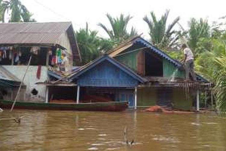 Warga terlihat membersihkan atap rumah menggunakan air banjir yang menggenangi Dusun Lubuk Dagang, Desa Lubuk Lagak, Kecamatan Sambas, Kabupaten Sambas, Kalbar (12/2/2016)