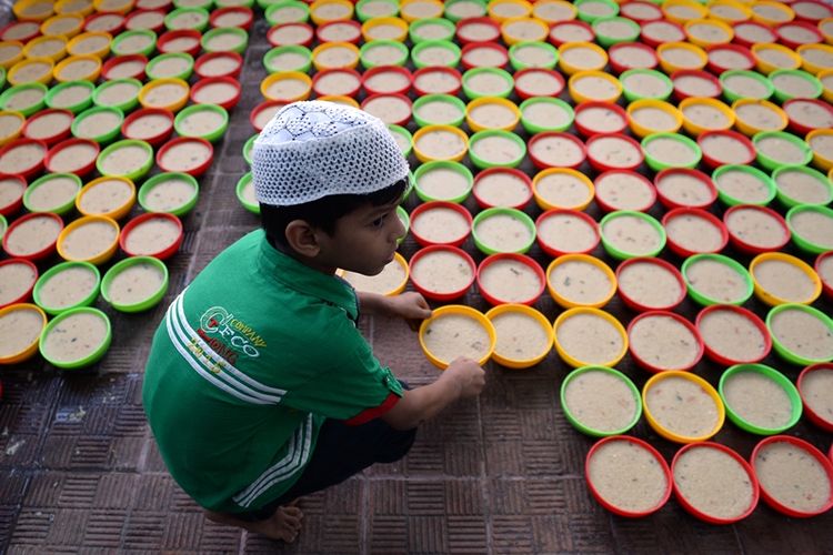 Seorang bocah laki-laki tengah membantu mempersiapkan makanan untuk berbuka puasa di masjid Wallajah, Chennai, India.