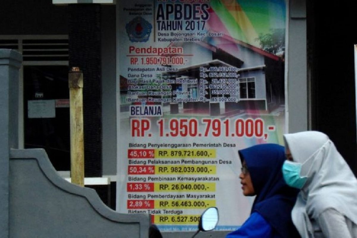 Warga melintasi spanduk pemberitahuan anggaran pendapatan dan belanja desa di Balai Desa Bojongsari, Kecamatan Losari, Kabupaten Cirebon, Jawa Barat, Minggu (9/7/2017). Setiap desa seharusnya memasang baliho di balai desa terkait laporan penggunaan dana desa. Ini untuk transparansi penggunaan dana desa. 
