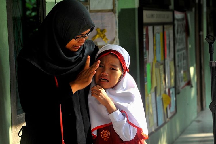 Seorang ibu menenangkan anaknya yang menangis saat hari pertama masuk sekolah di SD Negeri Sumber Agung, di Jalan Bayangkara, Serang, Banten, Senin (16/7). Pemerintah melalui Menteri Pendidikan mengingatkan pentingnya tanggung jawab orang tua membantu menyiapkan mental anak saat hari pertama masuk sekolah agar anak lebih percaya diri dan siap menyerap pelajaran di sekolah.