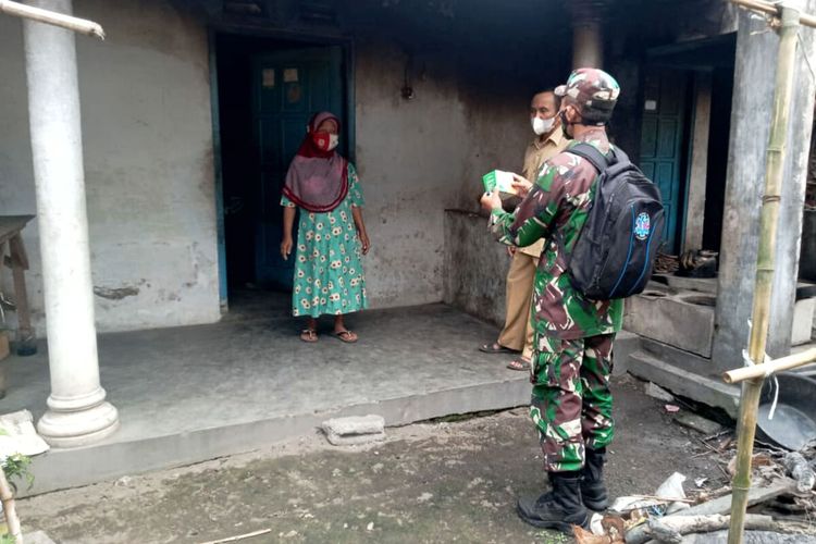 Seorang babinsa mengantarkan paket obat kepada seorang warga yang sedang isolasi mandiri di rumahnya di Desa Slorok, Kecamatan Garum, Kabupaten Blitar, Rabu (11/8/2021)