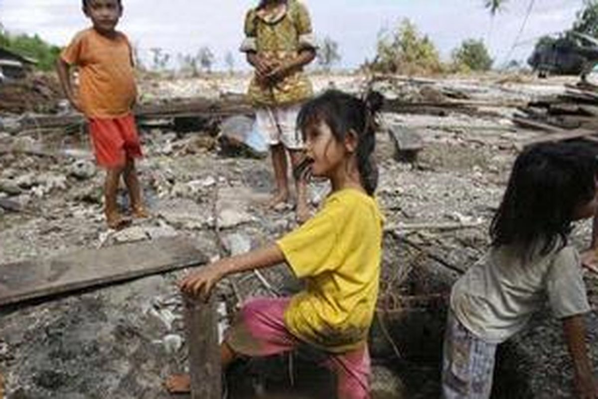 Anak kembar, Nila dan Lili (4) mencuci kaki di kubangan air di sekitar reruntuhan bangunan rumah yang hancur tersapu tsunami di Kampung Tumalei, Desa Silabu Kecamatan Saumanganya, Kabupaten Kepulauan Mentawai, Sumatera Barat, Minggu (31/10/2010). Warga terpaksa menggunakan air kotor untuk mencuci kaki karena sulitnya mendapatkan air bersih untuk kebutuhan MCK dan minum. 