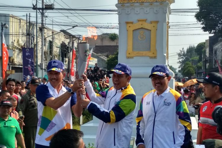 Wali Kota Yogyakarta, Haryadi Suyuti (tengah) saat menerima obor Asian Games 2018 dari Sekjen INASGOC, Eris Hariyanto (Kiri) di kawasan Monumen Tugu Yogyakarta, Kamis (19/7/2018)